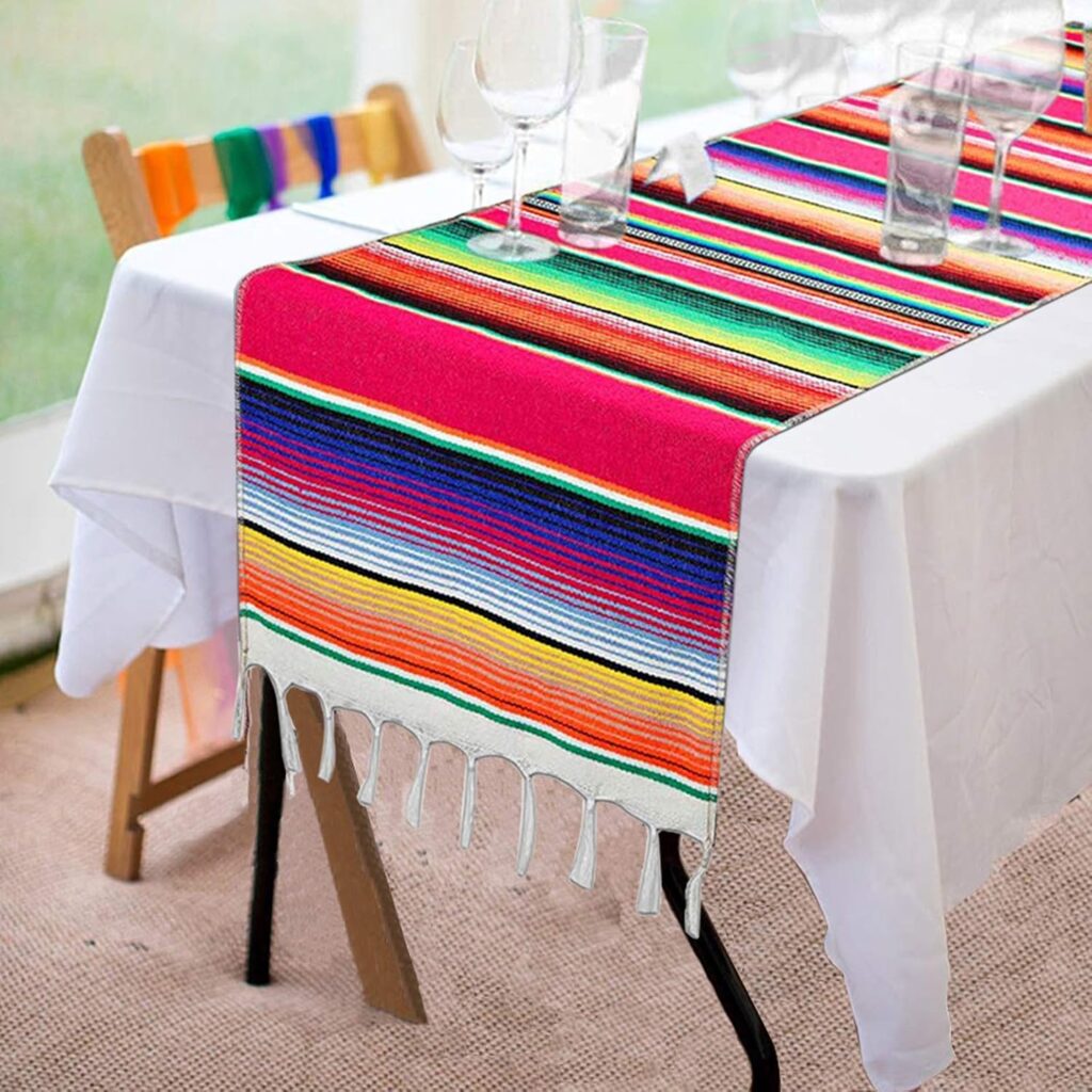 Colorful striped table runner with fringe on dining table with glassware