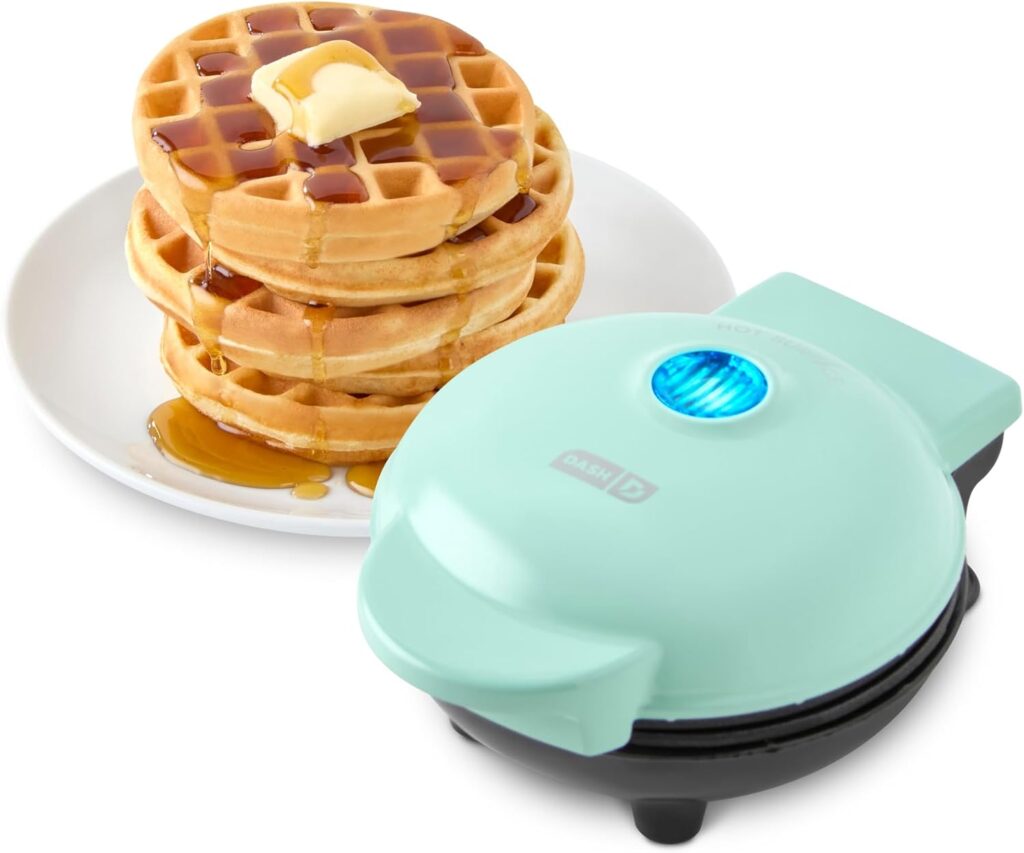 Mini waffle maker with round waffles on plate and syrup