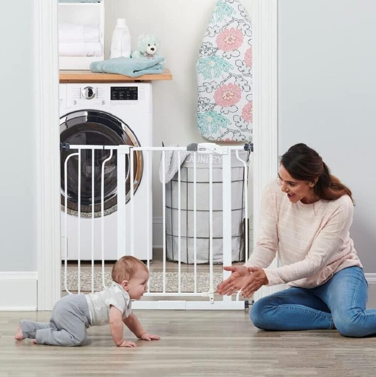 Baby crawling near safety gate in doorway with parent sitting nearby