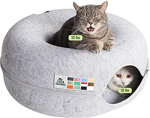 Light gray 3-in-1 donut-shaped cat cave and tunnel made of scratch-resistant felt. The image features a gray tabby cat lounging in the top recessed bed labeled '22 lbs' and a white cat peeking out from the side tunnel opening labeled '23 lbs', highlighting its capacity for large or multiple cats.